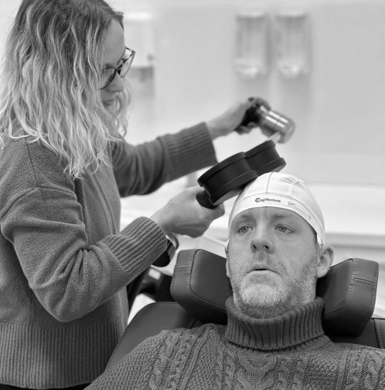 a woman holding a device to a man's head